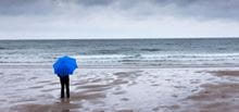 Person on beach looking out at stormy sea
